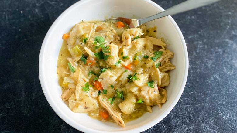 chicken and dumplings in a bowl with parsley garnish