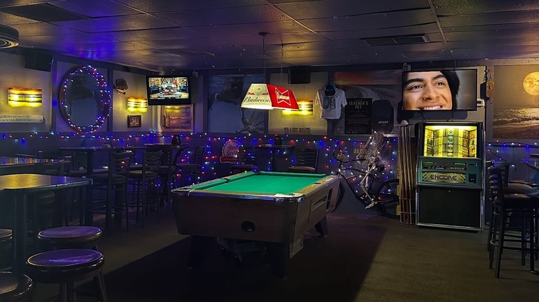 Inside of the Swizzle Inn, with a pool table, chairs, and a jukebox.
