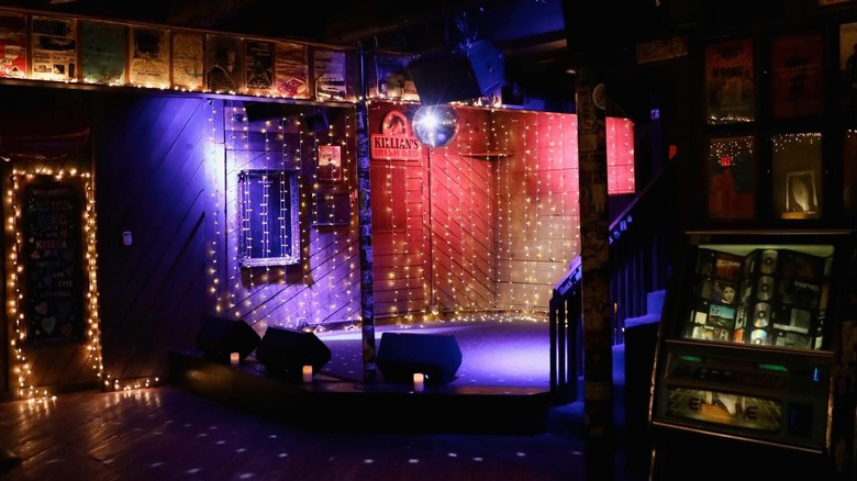 Inside of The White Water Tavern, with a stage with a disco ball on top and a jukebox to the right.