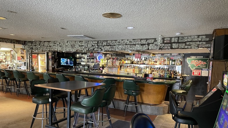 interior of a bar, with tables and chairs and dollar bills on the walls.