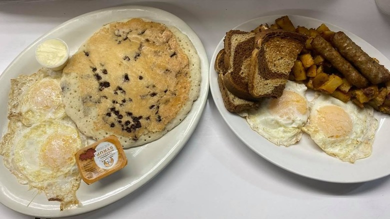 Plates of eggs, pancakes, toast, bacon, and home fries