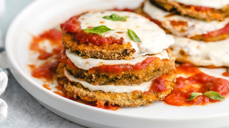 A close-up shot of eggplant parmesan on a white plate