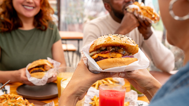 Unidentifiable people eating burgers in a diner