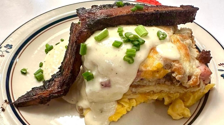 Pancake lasagna made with pancakes, scrambled eggs, sausage, pork belly bechamel, cheddar, and cheese