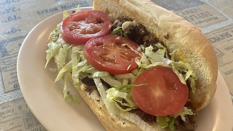 A chopped cheese sandwich on a roll with lettuce, tomato and mayonnaise