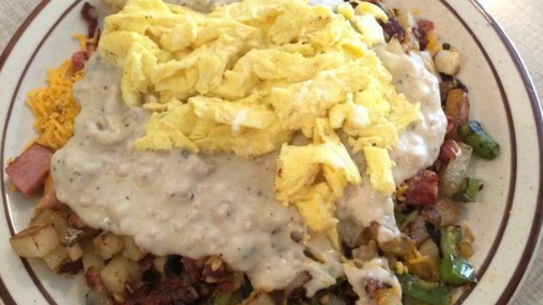A plate piled with eggs, gravy, veggies, meat, and home fries at Joe Brown's Cafe