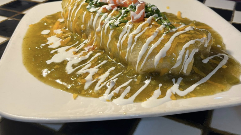 A large burrito smothered in green sauce and crema at Luxury Diner