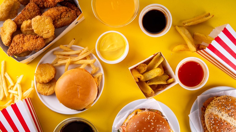 Spread of various fast food foods -- burgers fries, chicken tenders, and sauces.