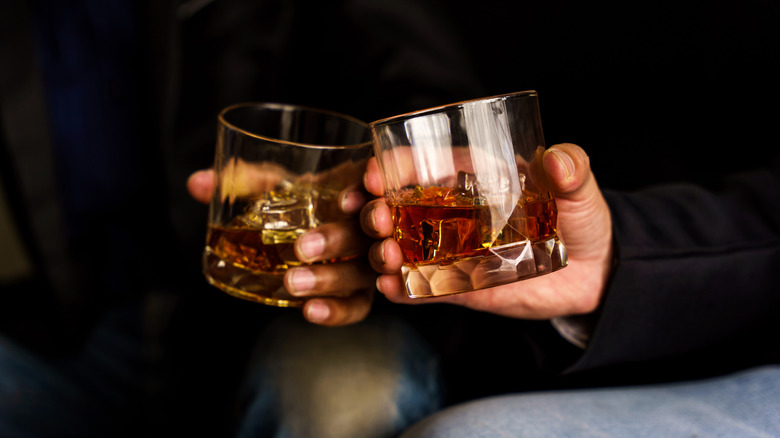 Two people toasting glasses of whisky.
