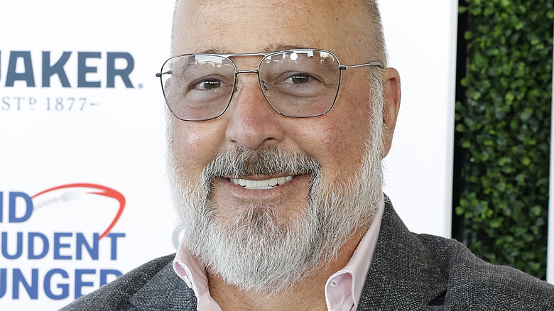 Andrew Zimmern smiling and wearing glasses.