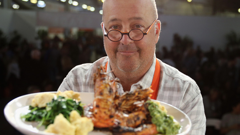 Andrew Zimmern holding plate of food