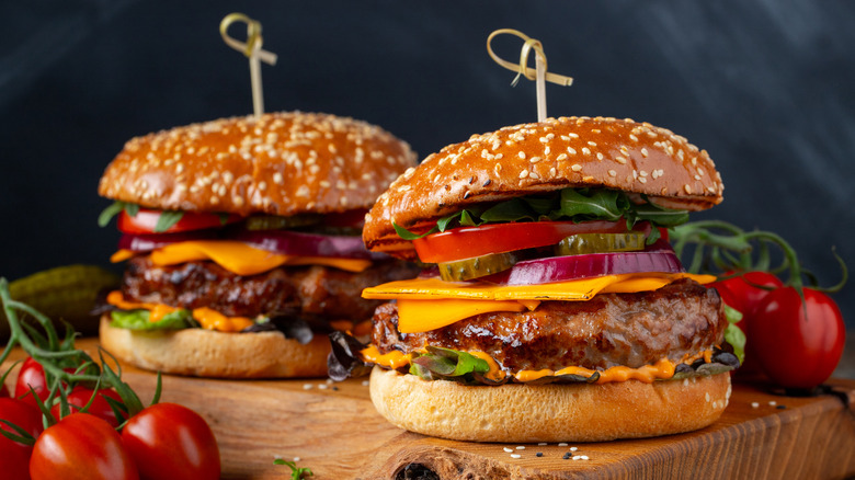 two cheeseburgers on wooden board