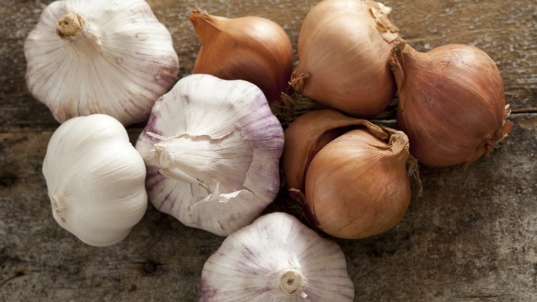Raw garlic and onions on wood surface.