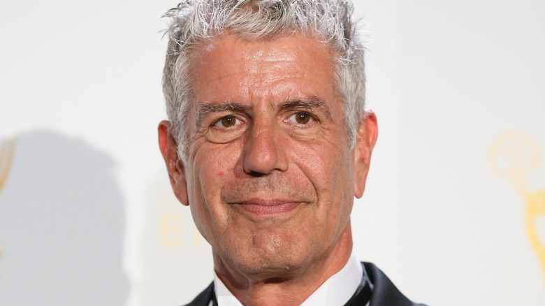 Anthony bourdain smiling in suit against white background