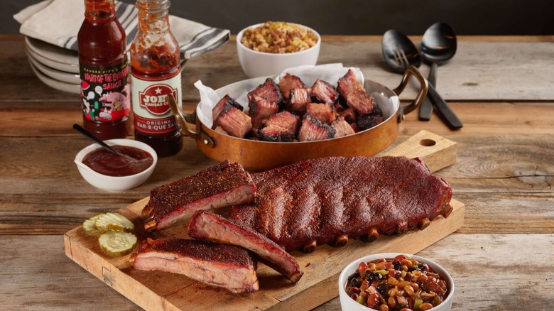 Ribs, burnt ends, barbecue sauce, and beans on wooden table
