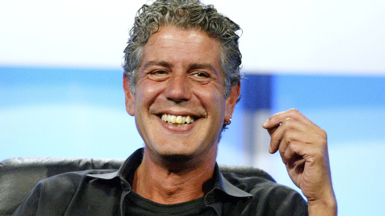 Anthony Bourdain seated in chair smiling