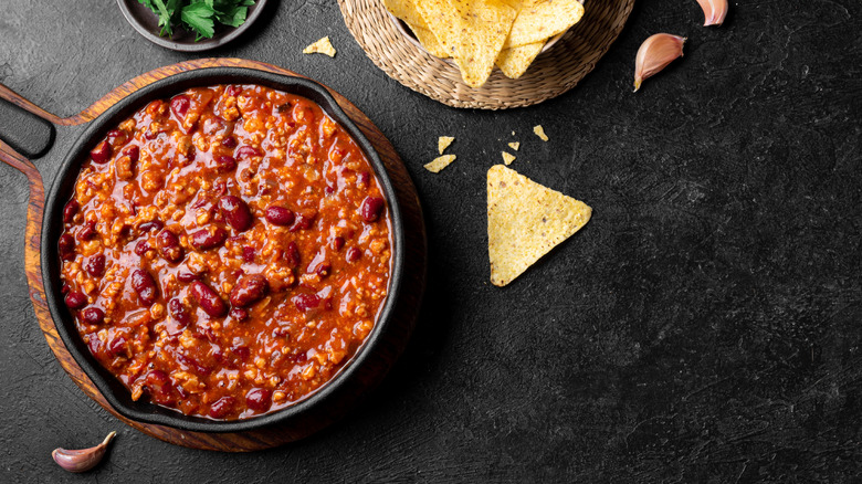 skillet of chilli with herbs and tortilla chips