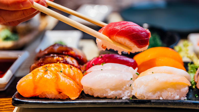Person picking up sushi with chopsticks