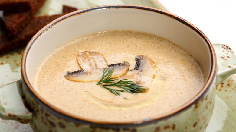 Creamy soup with mushroom and herb garnish.