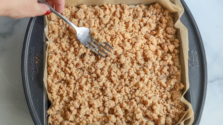 Crumb-topped coffee cake in pan with fork on top