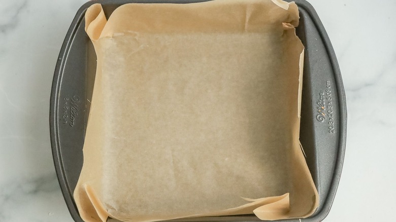 Square baking pan lined with parchment paper