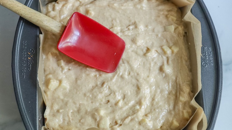 Rubber spatula smoothing out coffee cake batter in pan