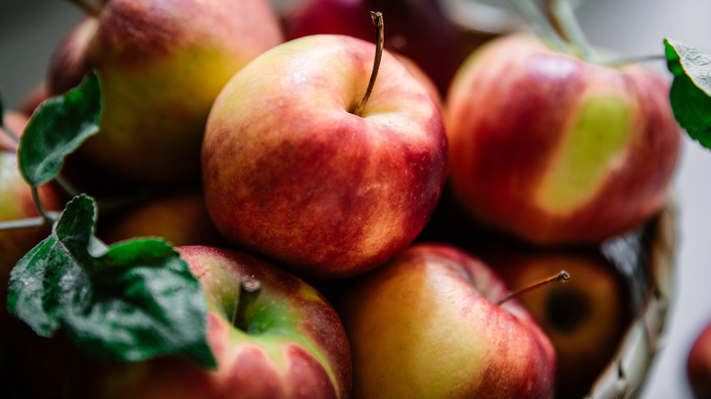Closeup of fresh apples in a basket with green leaves