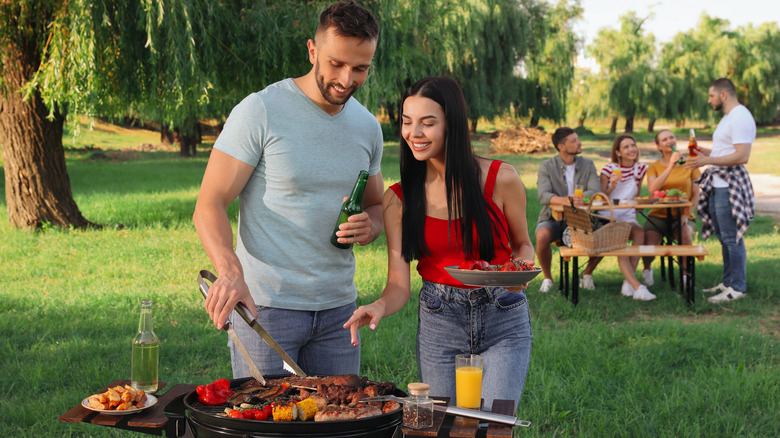 Two people grilling foods for friends
