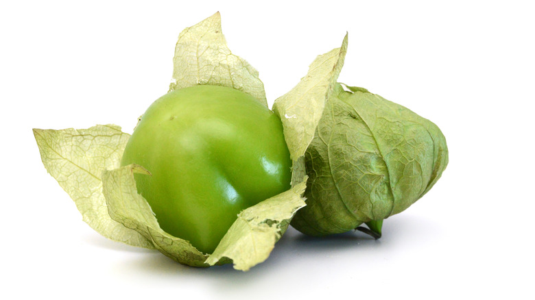 two tomatillos, one unwrapped