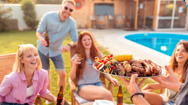 People enjoying a cookout poolside