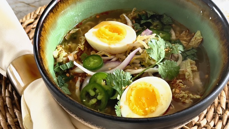 Ramen in brown and green bowl with soft boiled egg
