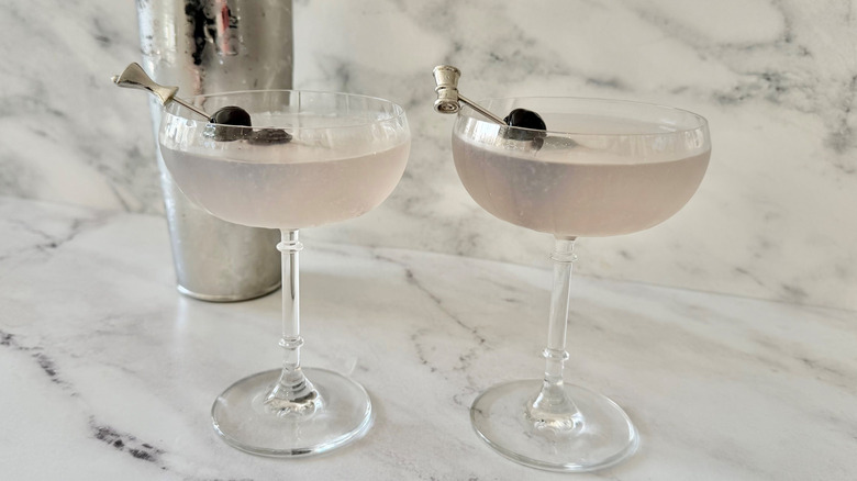 Aviation cocktails garnished with cherry skewers in front of cocktail shaker