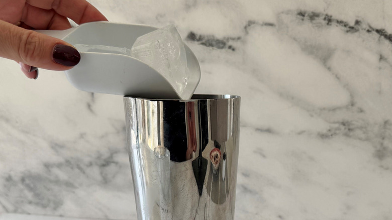 Hand scooping ice into cocktail shaker