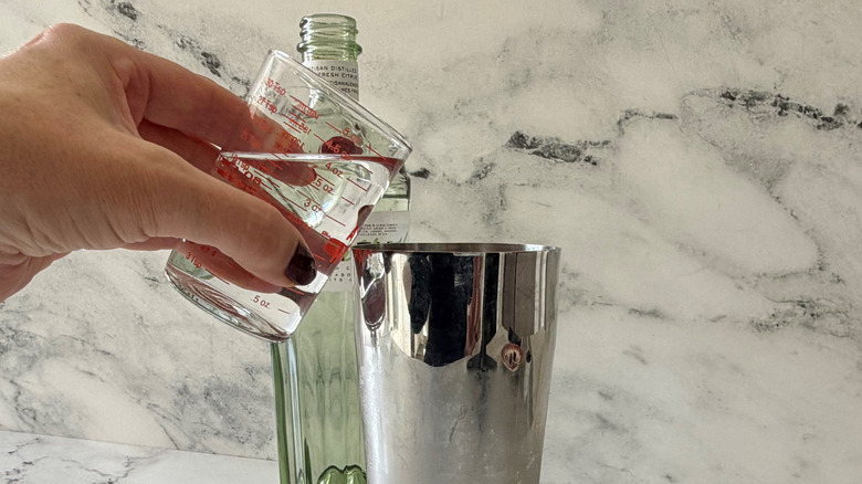 Hand pouring gin into cocktail shaker