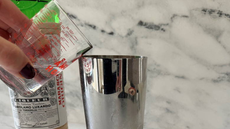 Hand pouring liqueur into cocktail shaker