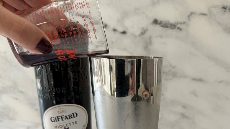 Hand pouring liqueur into cocktail shaker