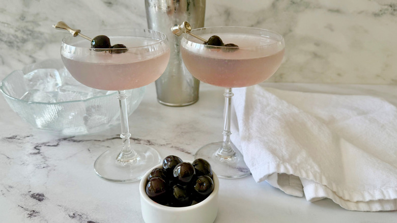 Aviation cocktails next to bowl of ice, napkin, and bowl of cherries
