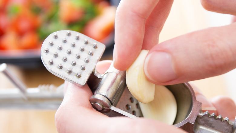 Hand placing garlic cloves into garlic press