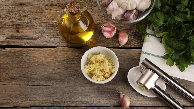 Oil bottle, garlic press, and garlic on table