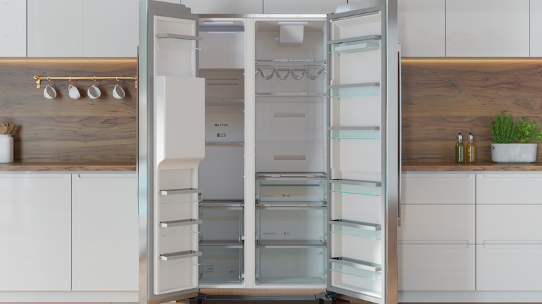 empty refrigerator with doors open in kitchen