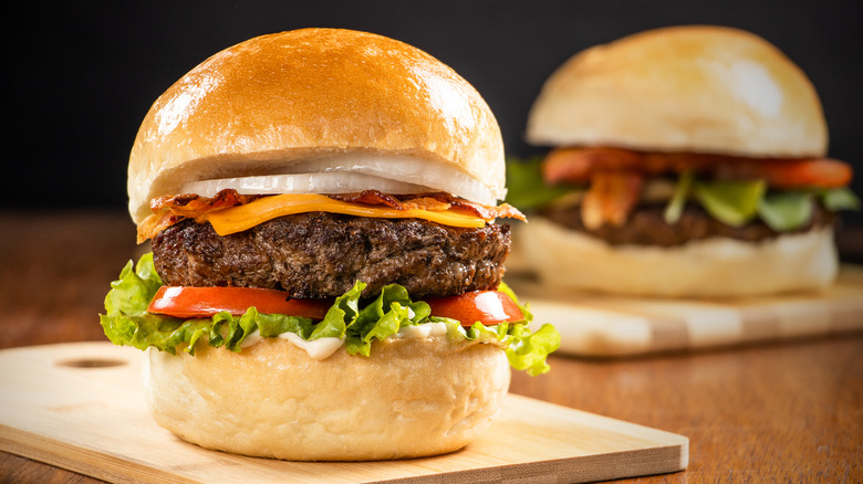 large cheeseburger on wood plate