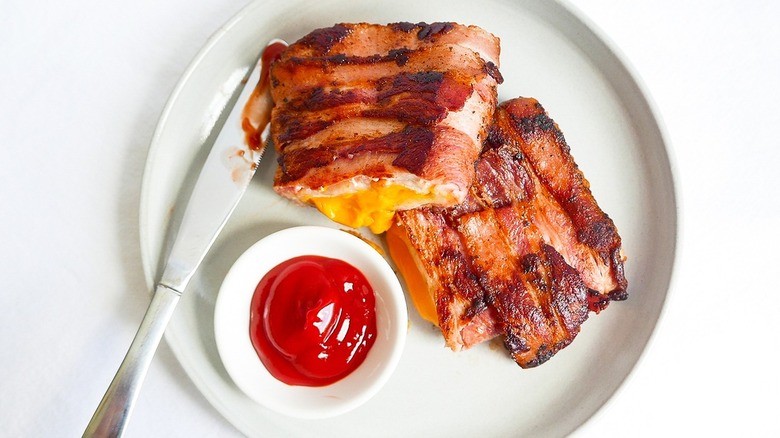 Bacon grilled cheese sits on a plate with ketchup 
