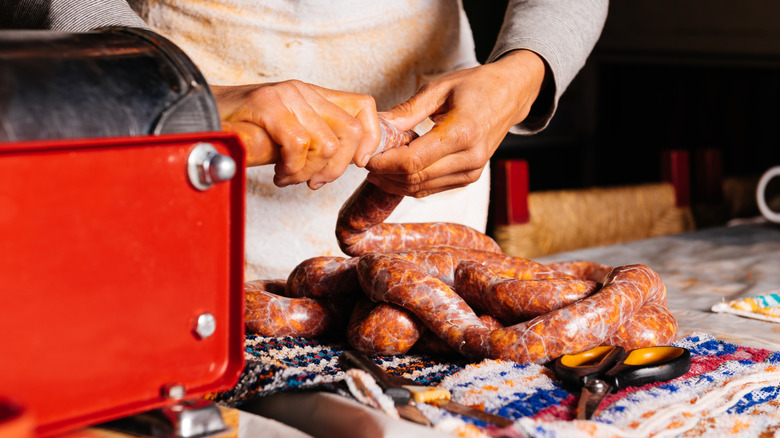 Person encasing sausages and twisting into links
