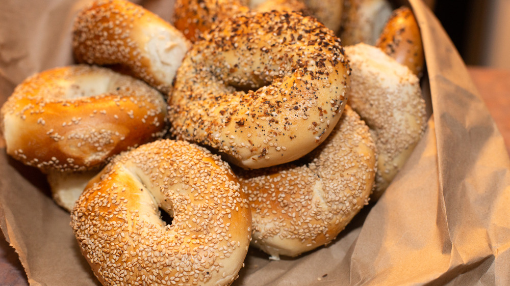 Variety of assorted authentic New York style Bagels with seeds in a brown paper bag.