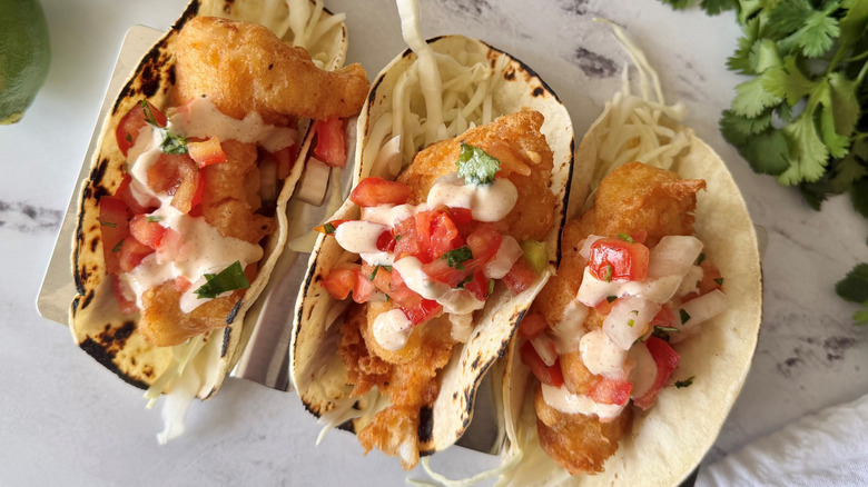 Baja style fish tacos topped with pico de gallo and crema