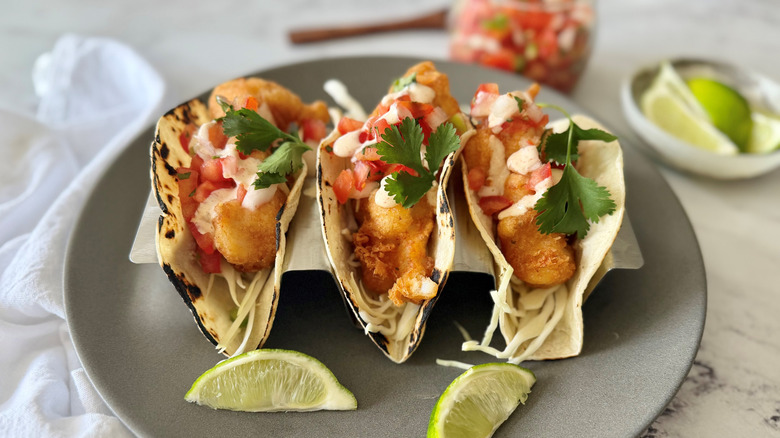 Baja fish tacos with pico de gallo, cilantro, and lime wedges