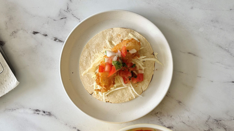 Fish taco topped with pico de gallo