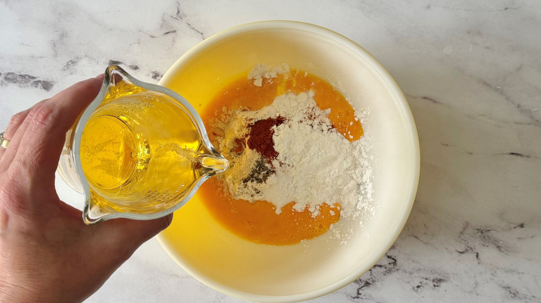 Hand pouring beer into mixture in bowl