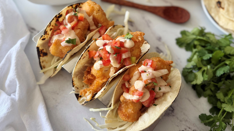Fried fish tacos topped with pico de gallo and crema