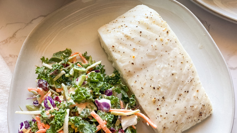 A Baked Halibut Filet on a plate with a salad